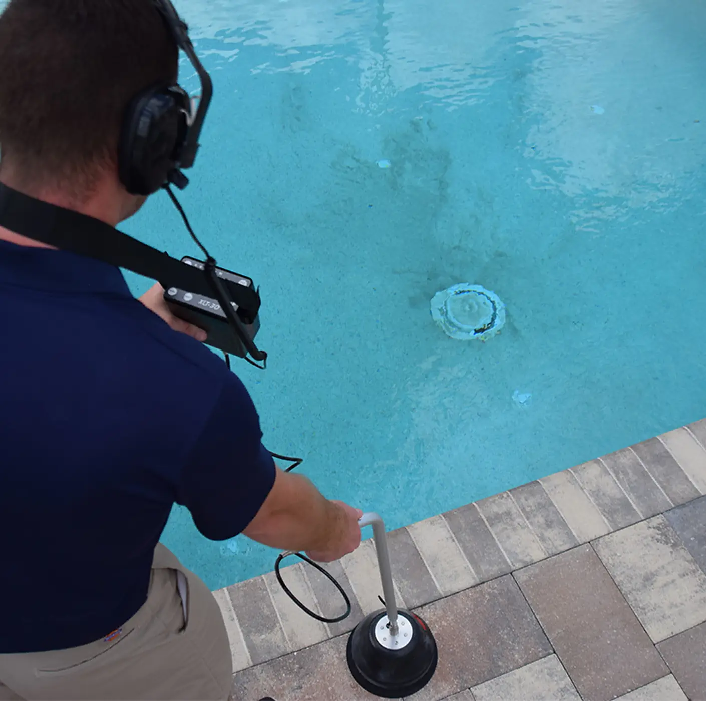 Profissional realizando detecção de vazamento de água com geofone ao lado de uma piscina