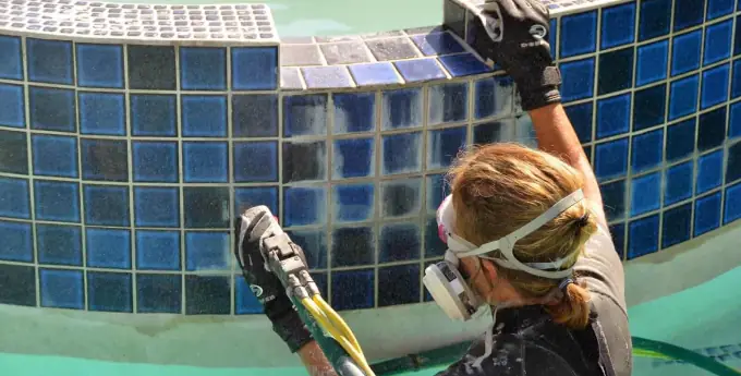 Profissional aplicando resina em piscina para resolver vazamento de água